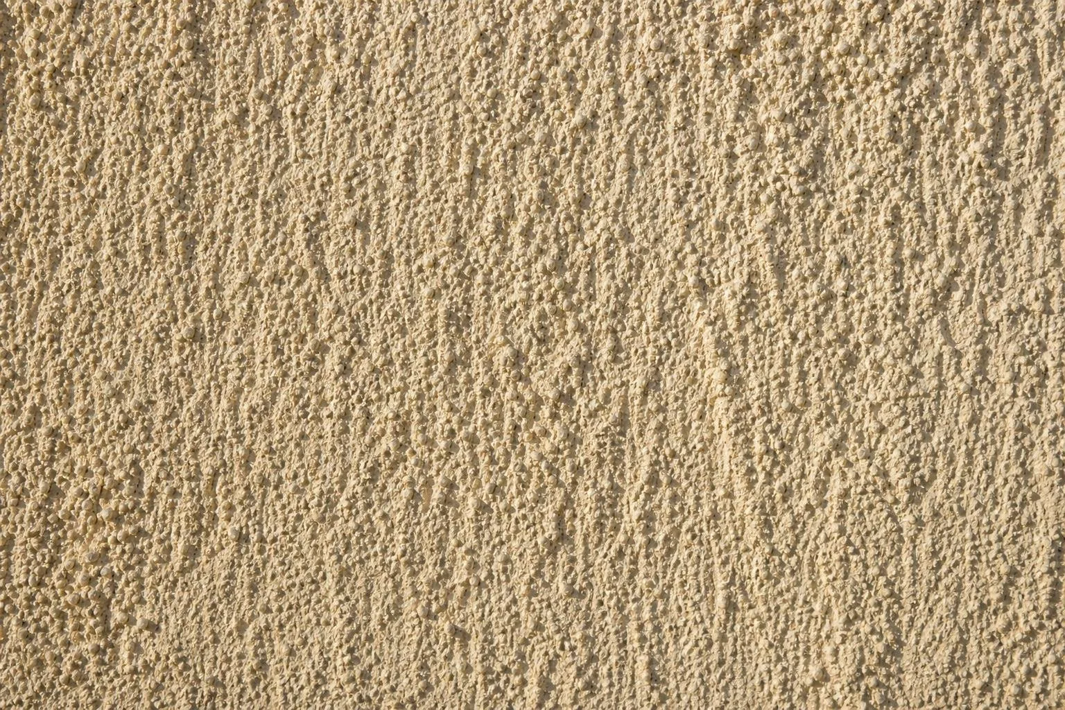 Detalle de la textura de un monocapa raspado en tono arena