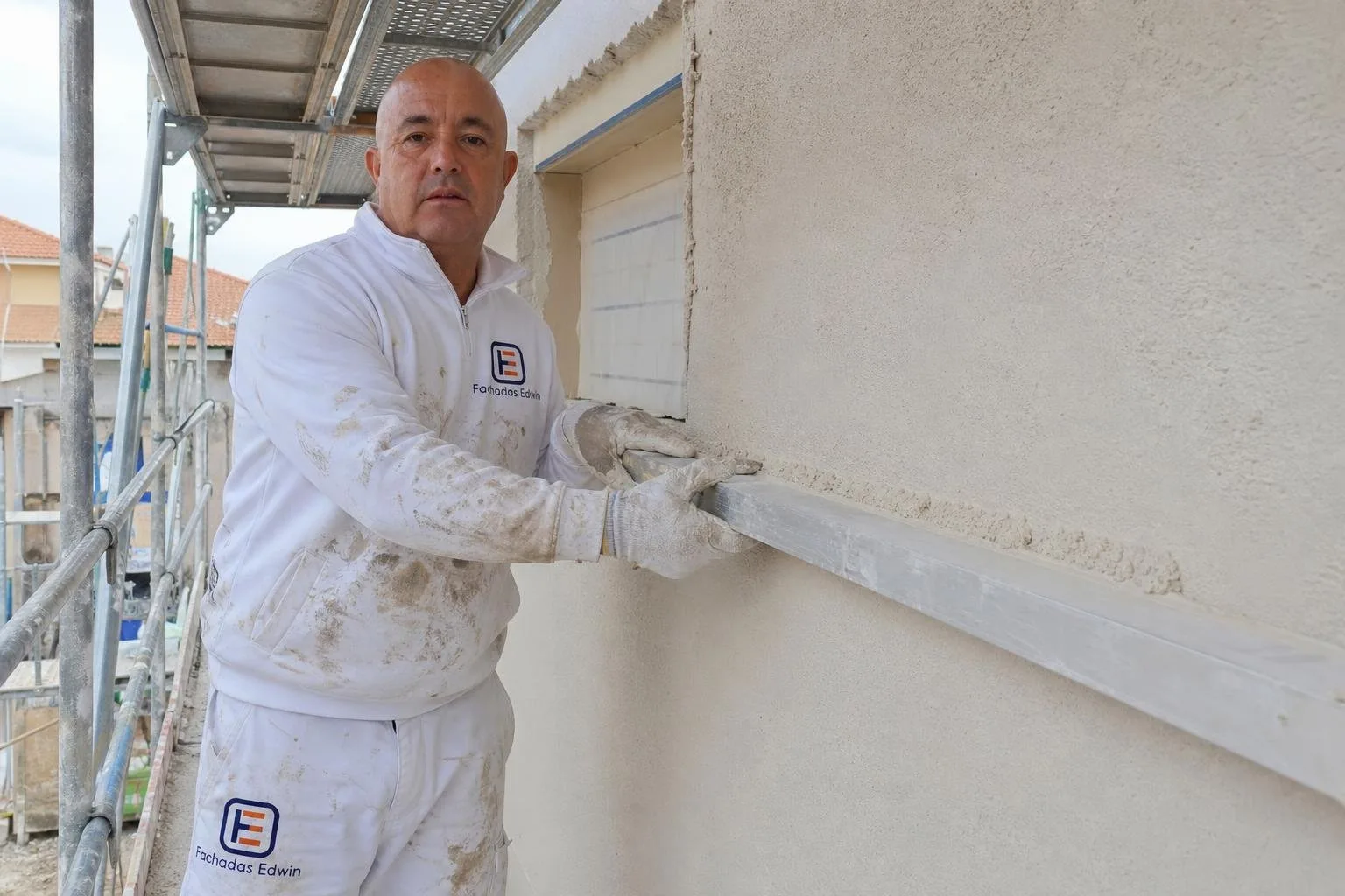 Edwin proyectando monocapa en la fachada de una vivienda de obra nueva